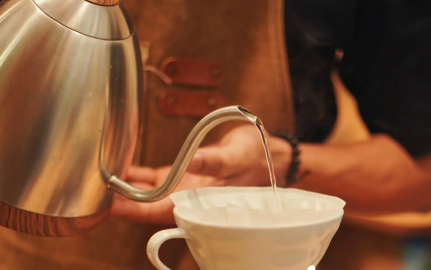 Gooseneck kettle pouring a thin stream into a white ceramic dripper